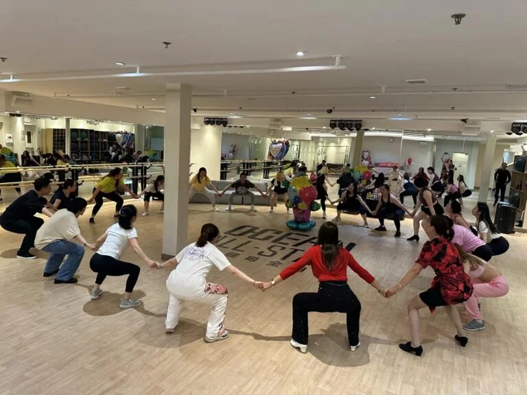 Trainer leads everyone hand in hand half-squat building collective wisdom and strength